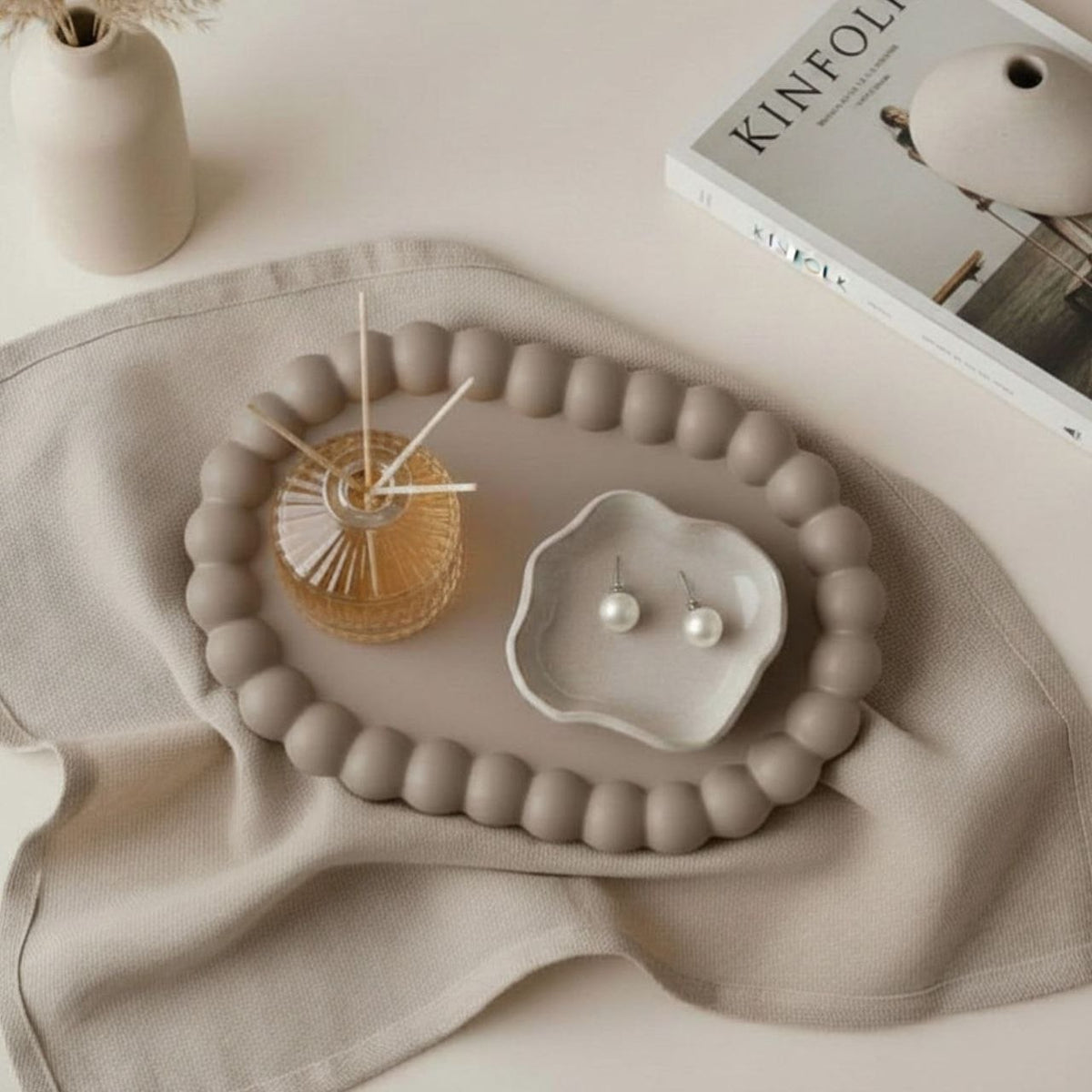 Oval bubble tray in a taupe finish with a diffuser and ceramic tray and neutral decor in the background