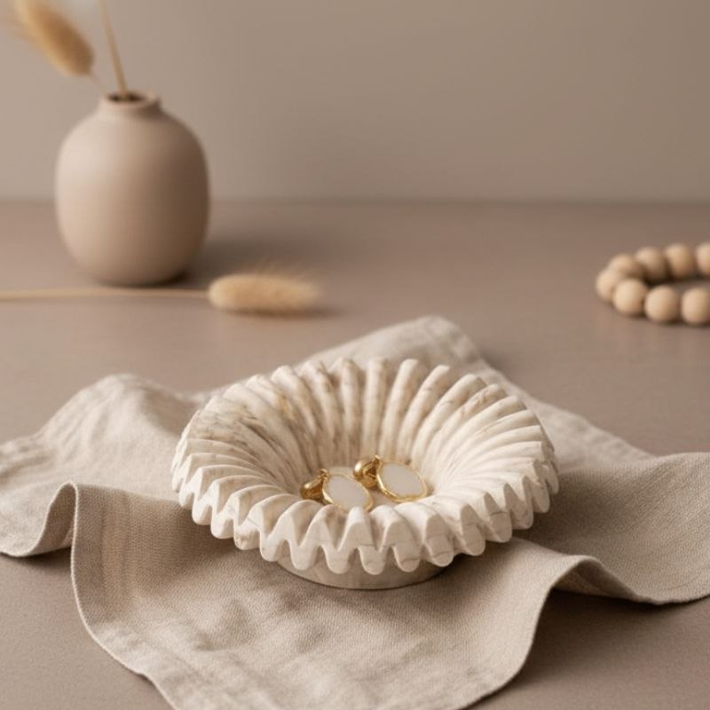 Ripple tray with marble finish with jewellery on beige fabric, a vase in the background