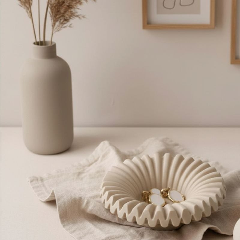 Ripple tray with taupe finish with gold ear rings on fabric, a vase and framed prints