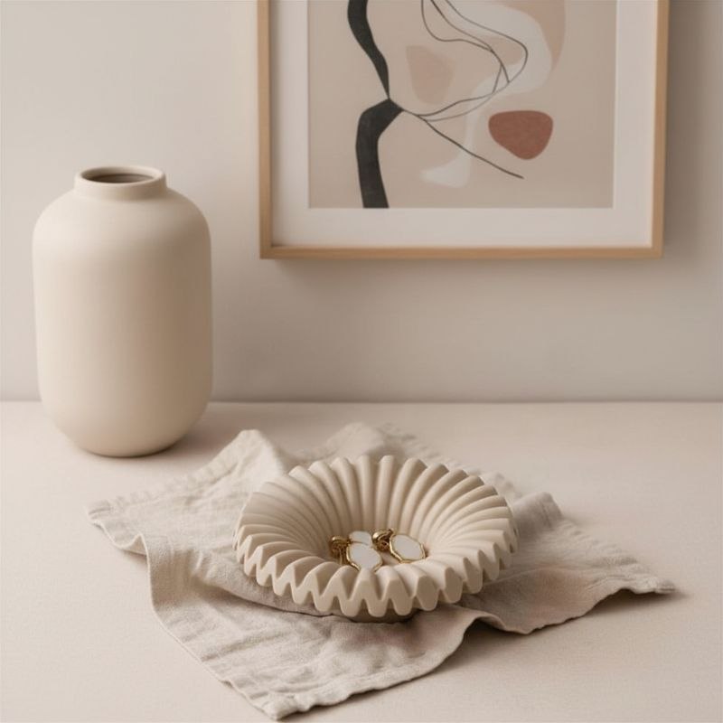 Ripple tray with taupe finish with gold ear rings on fabric, a vase and framed print