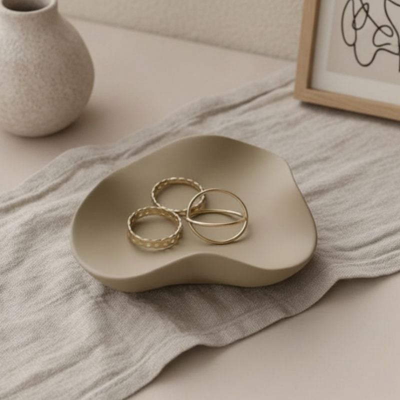 Wave tray with taupe finish with gold jewellery, a vase and a framed print