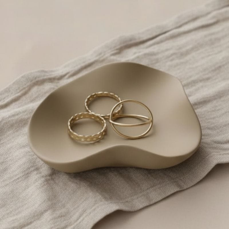 Wave tray with taupe finish with gold jewellery on beige fabric