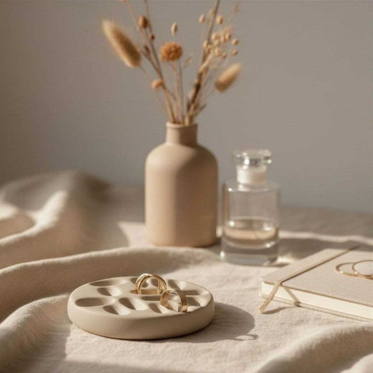 Taupe jewelry tray with gold rings on a beige background with a vase and decor