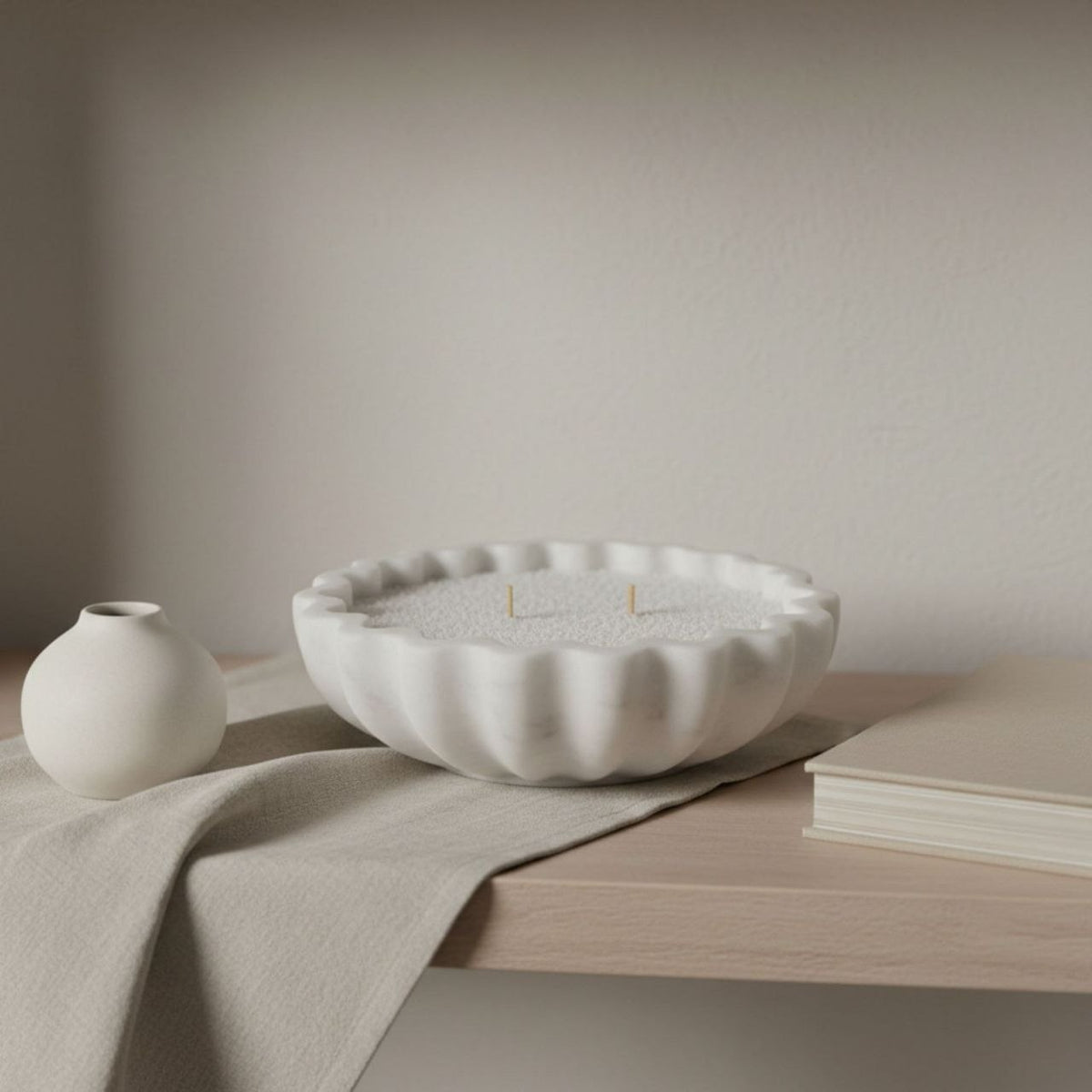 Fluted bowl with a natural finish on a shelf with a vase and a book