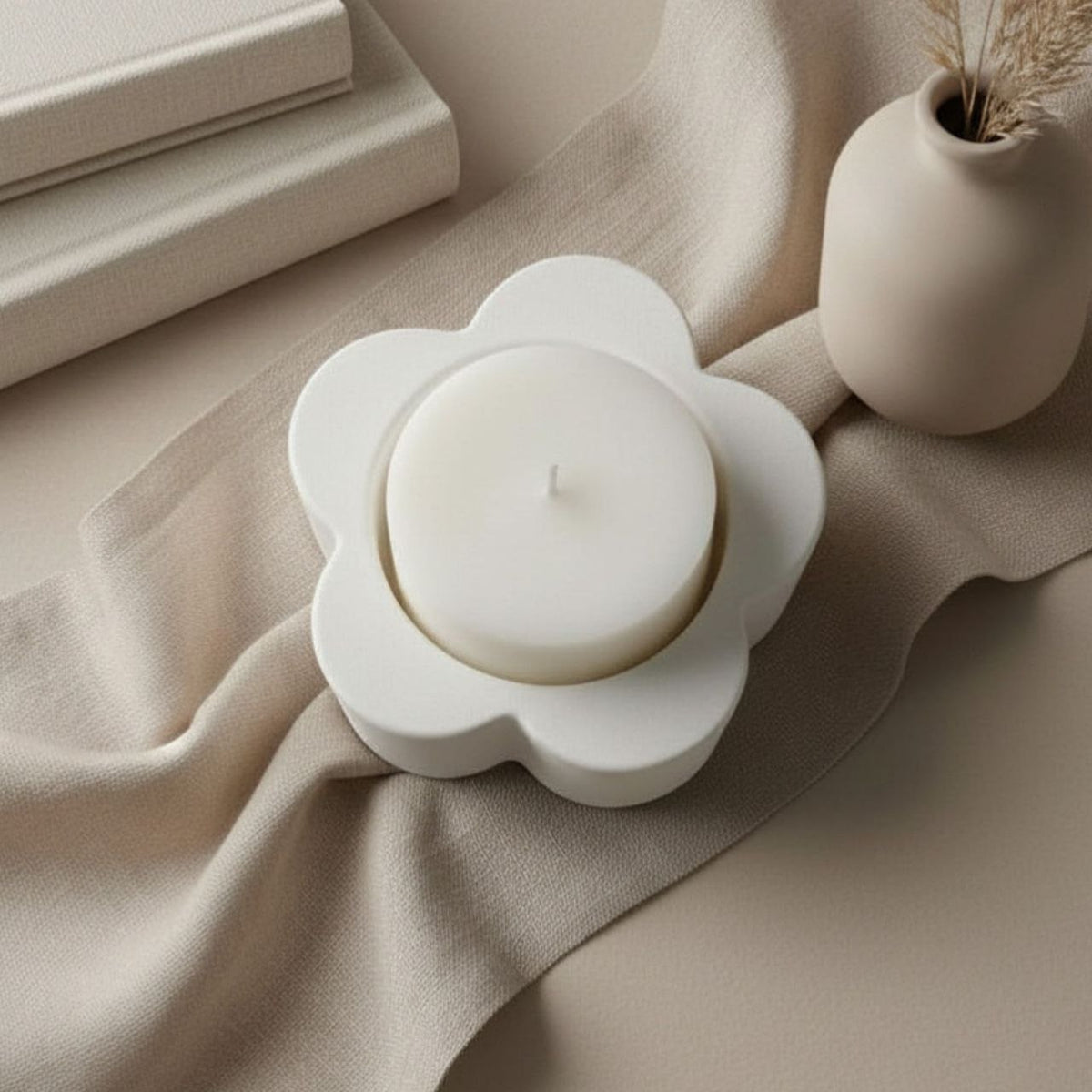 A white candle in a daisy candle holder with a ceramic vase