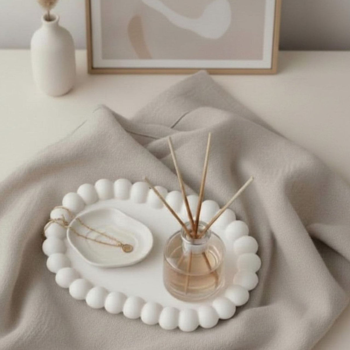 Oval bubble tray in a natural finish with a diffuser and ceramic dish and neutral decor in the background