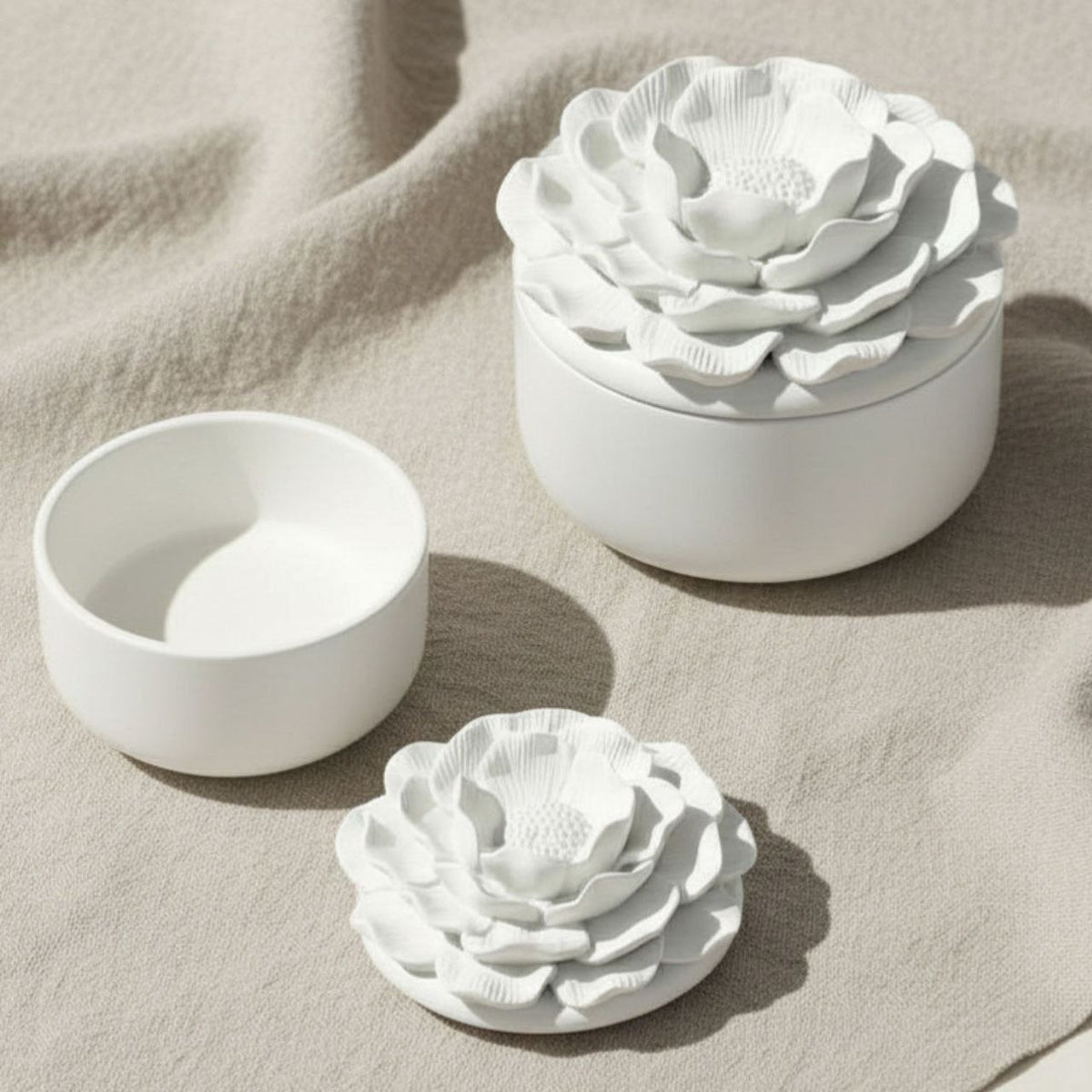 Small and large Camelia jar and lid with a natural finish on a beige fabric background