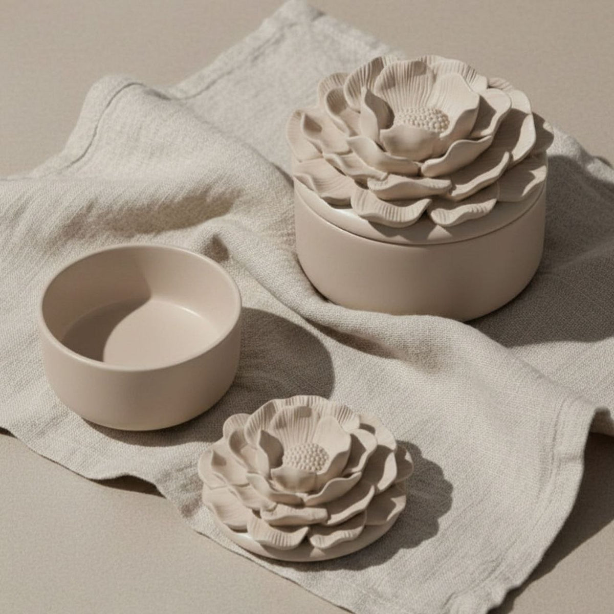 Small and large Camelia jar and lid with a taupe finish on a fabric background