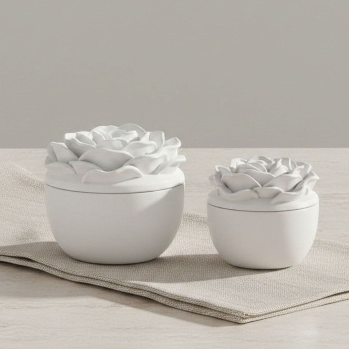 Small and large Rose jar and lid in a natural finish on folded fabric