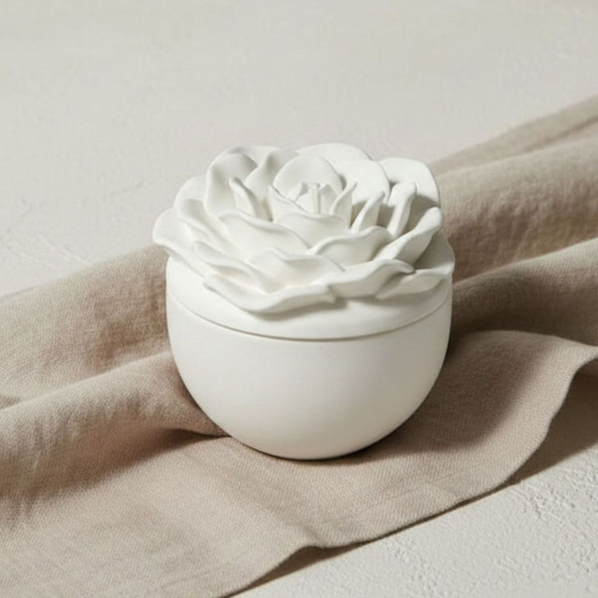 Rose jar and lid in a natural finish on beige fabric