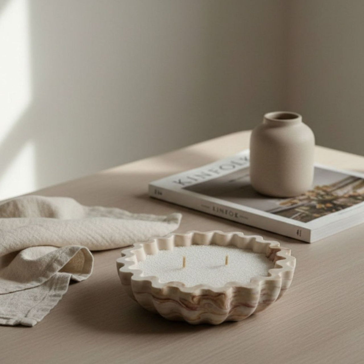 Fluted bowl with a burgundy and brown marble finish on a table with a magazine and a vase