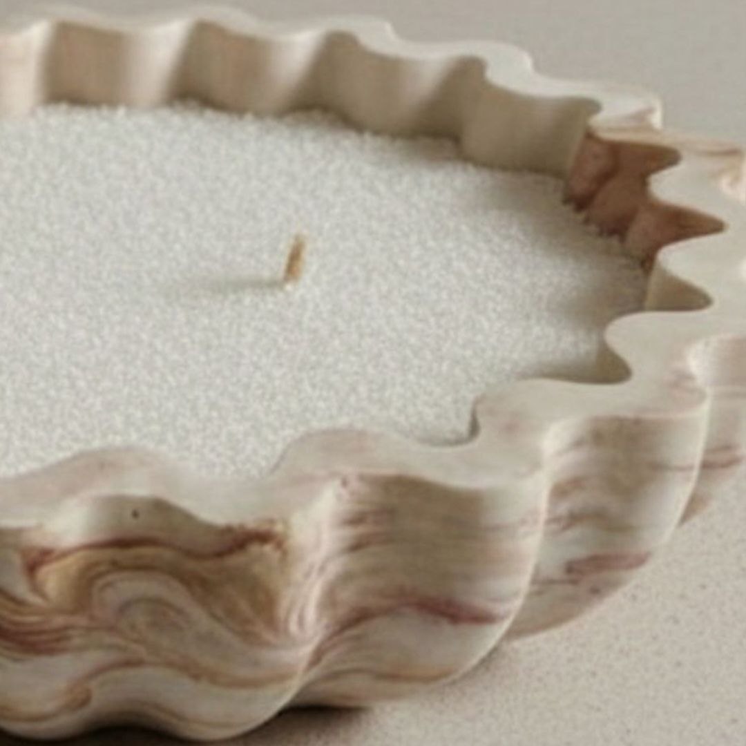 Close up of a fluted bowl with a burgundy and brown marble finish and wax sand