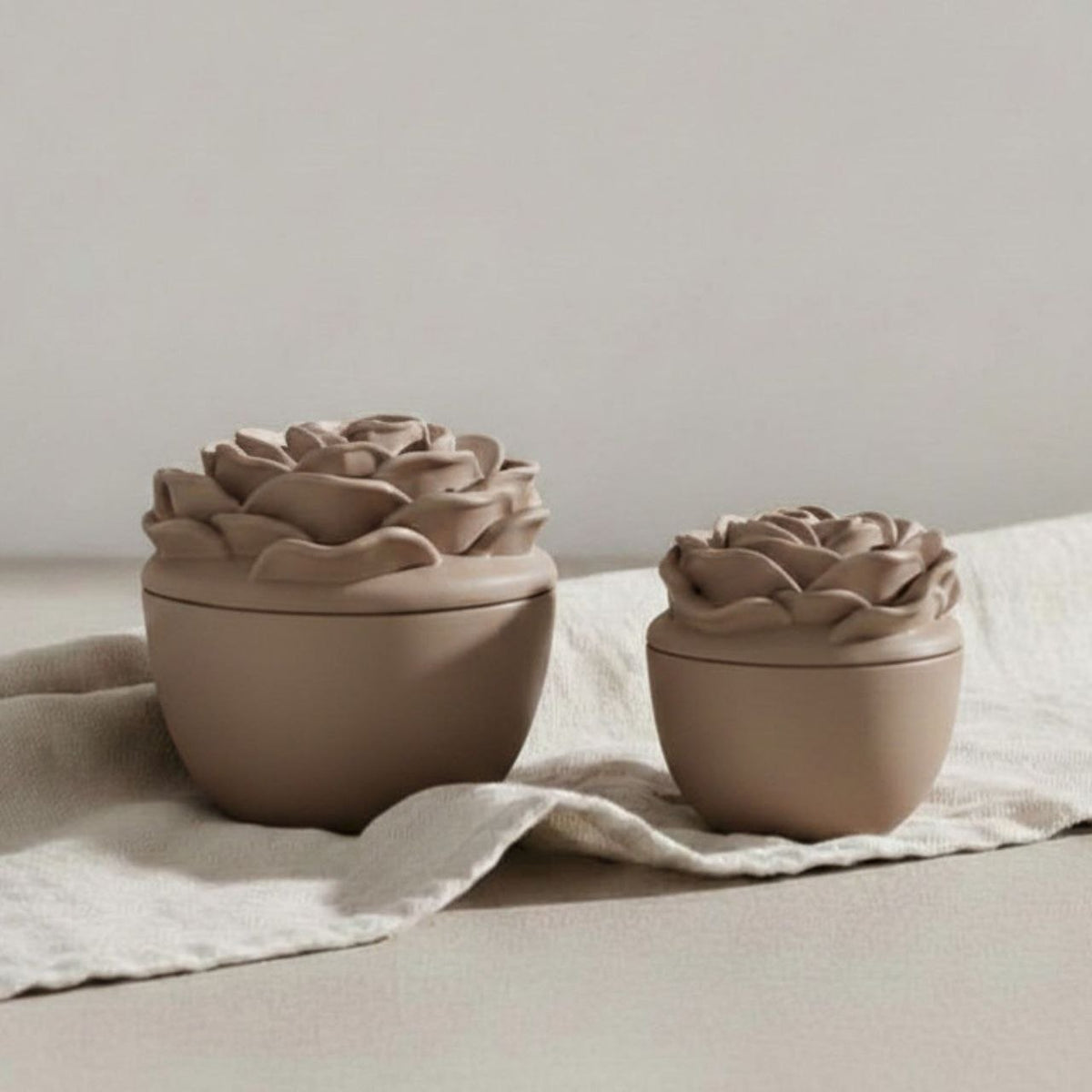 Small and large Rose jar and lid in a taupe finish on a fabric background