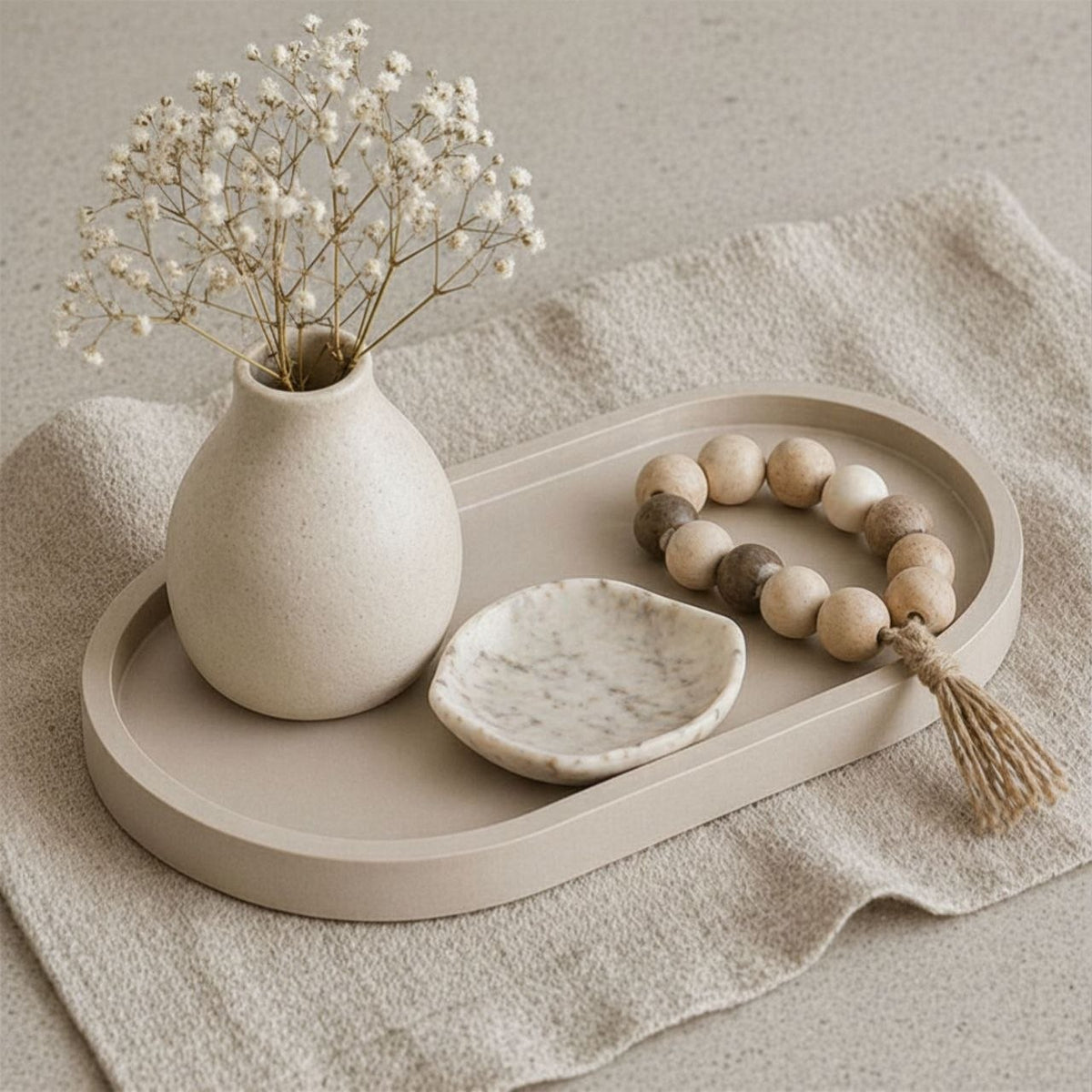 Beige Decorative tray with a vase, bowl, and beads on a neutral background