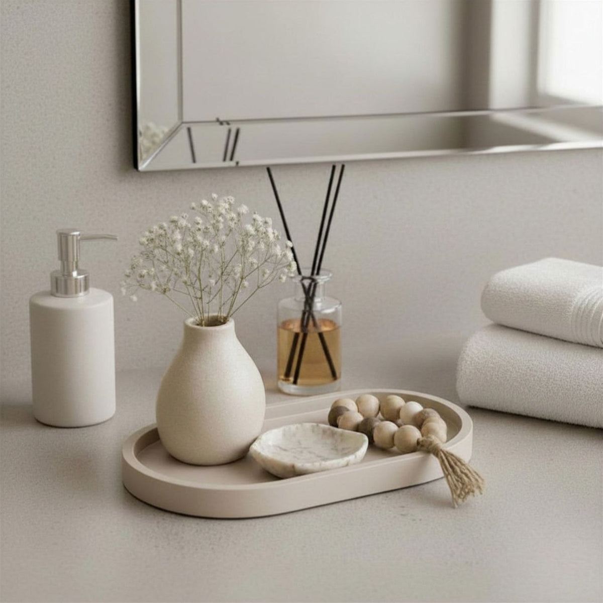 Bathroom counter with decorative items including a vase, diffuser,  oval tray and soap dispenser.