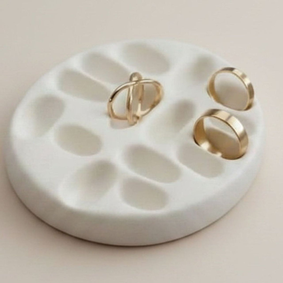 Natural finish jewelry tray with gold rings on a beige background