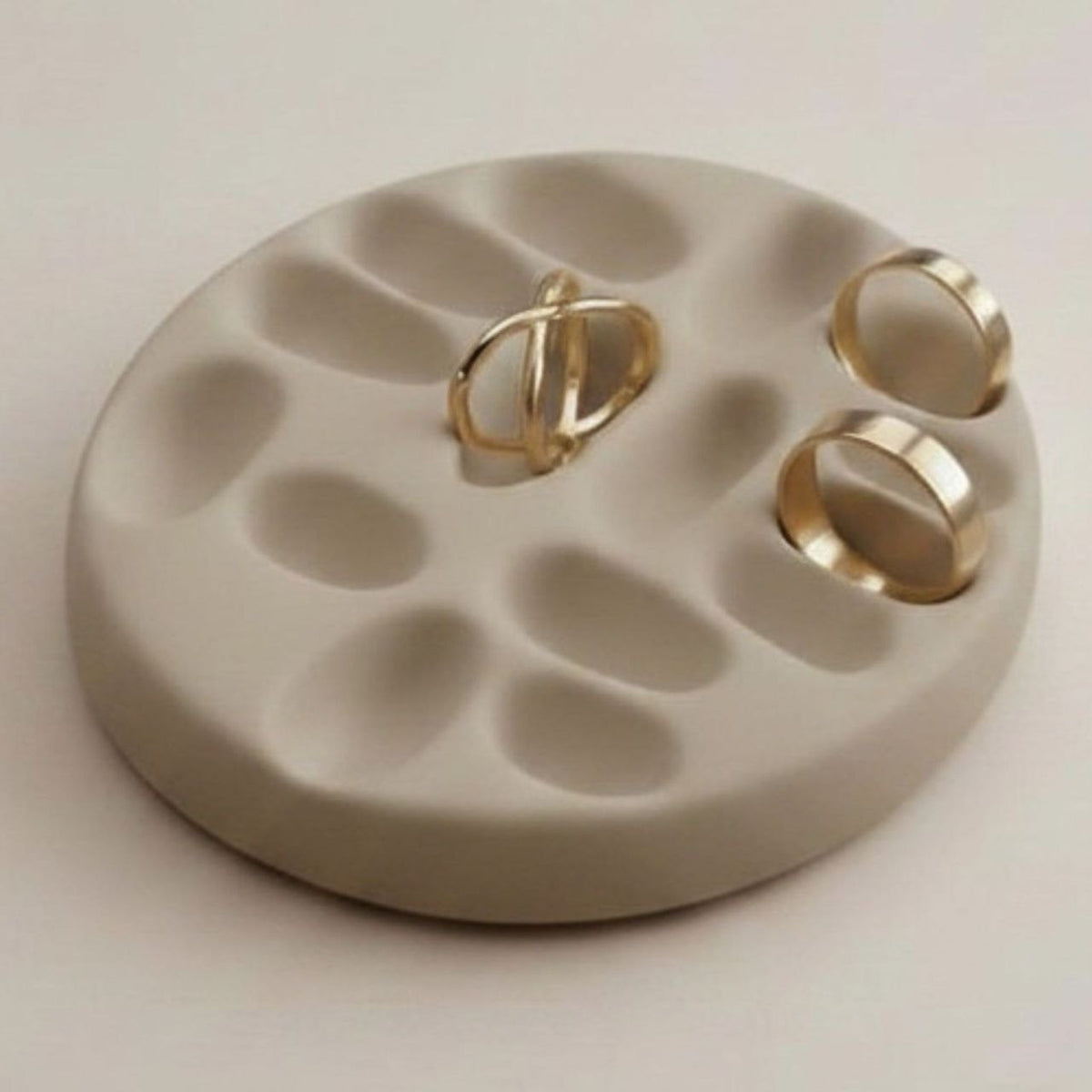 Round taupe jewelry tray with gold rings 