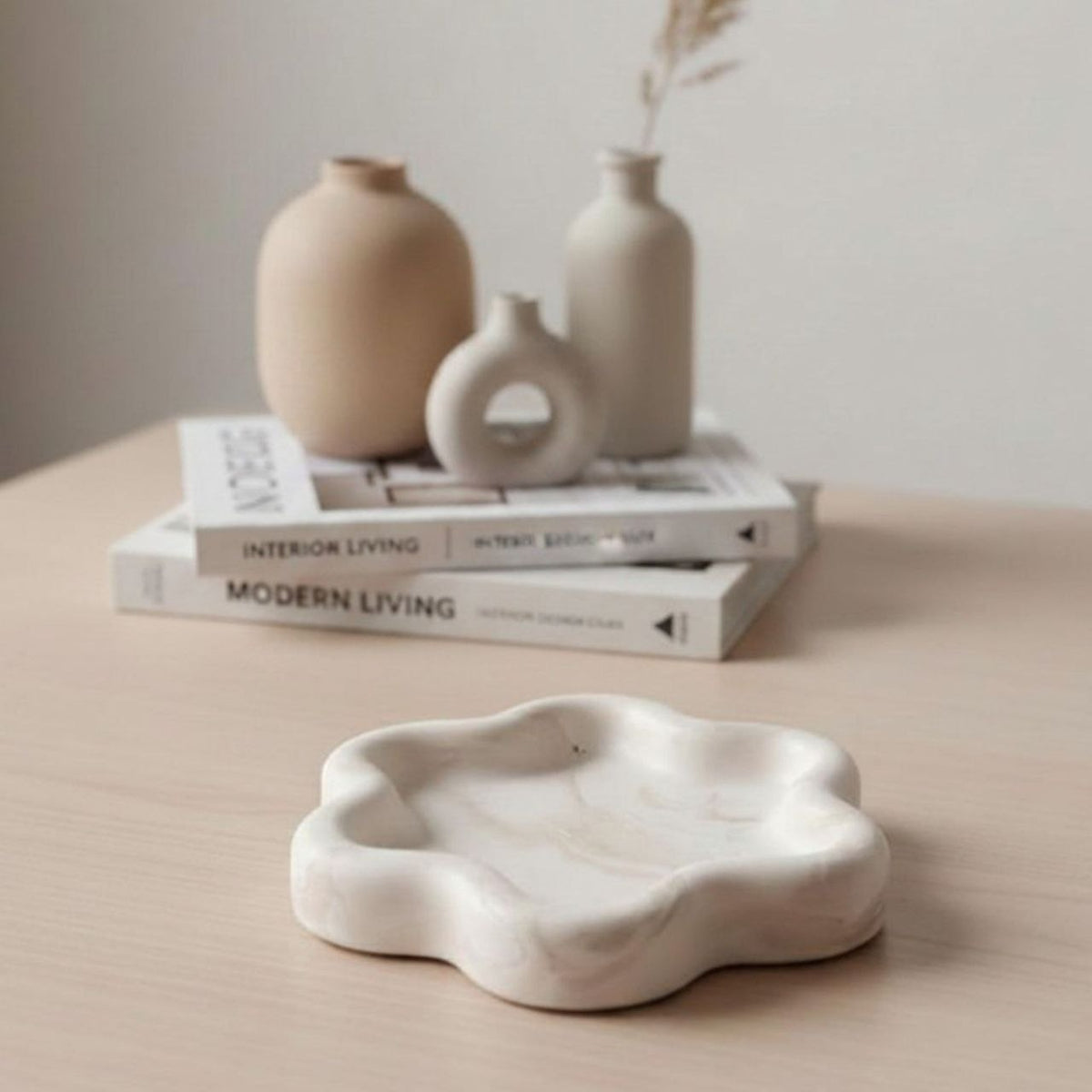 Marble effect flower tray on a table with books and vases in the background


