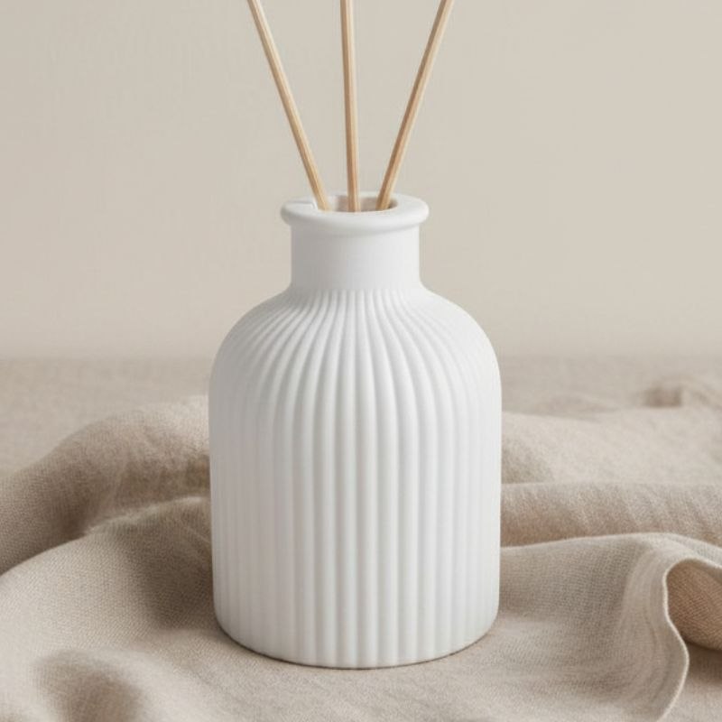 Natural reed diffuser on a fabric background.