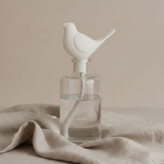 Bird Diffuser topper in a diffuser bottle on a fabric background