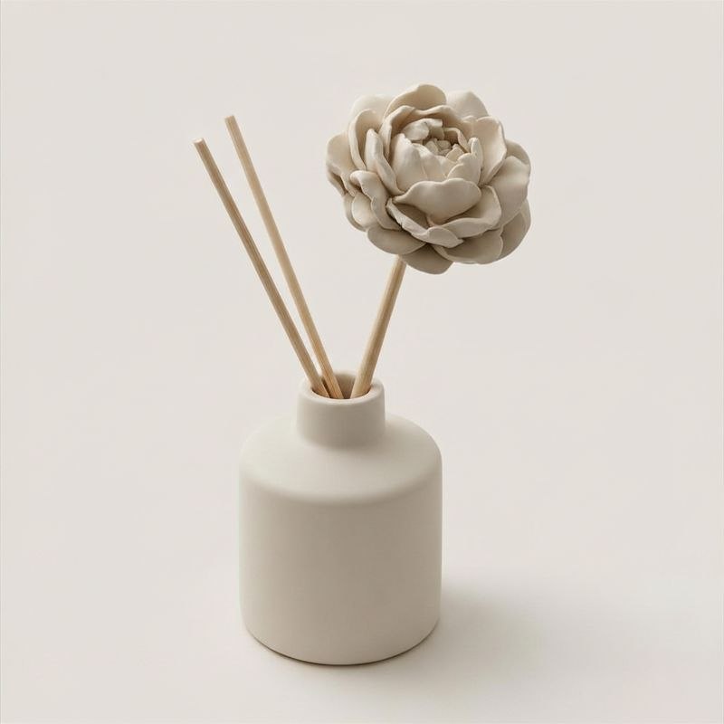 White ceramic diffuser with peony diffuser stick and reeds on a light background