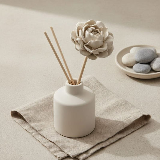 White ceramic diffuser with greige peony diffuser stick on a beige surface
